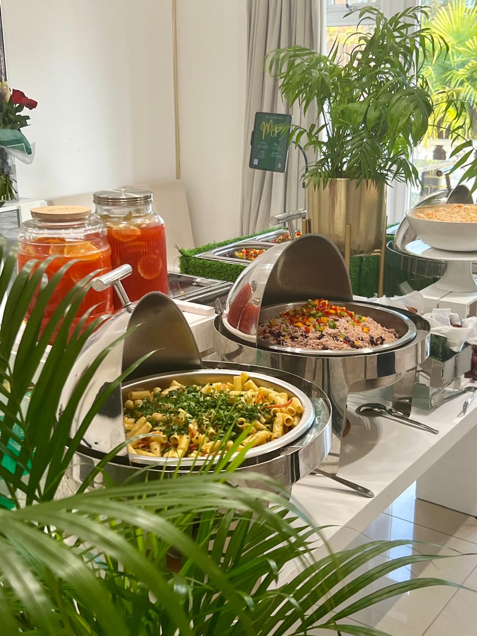 Caribbean buffet spread with rice and peas, pasta, and tropical drinks